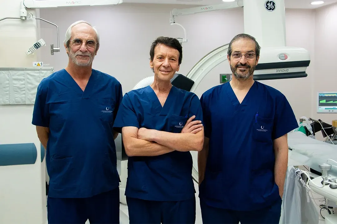 Tres médicos en la sala de procedimientos, junto al arco quirúrgico
